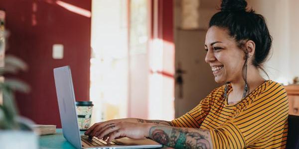 Woman at a laptop typing and smiling