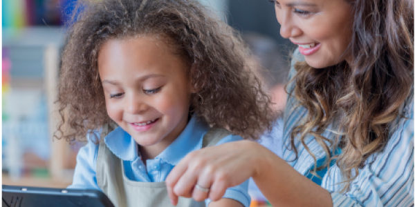 Preschool child using tablet with teacher