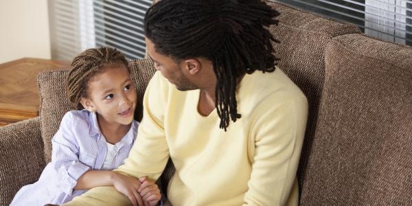 a parent talking to a child on the sofa