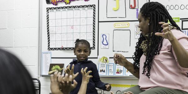 An educator and student performing in front of a classroom