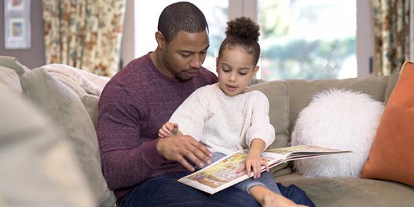 Young girl reading a book with her father