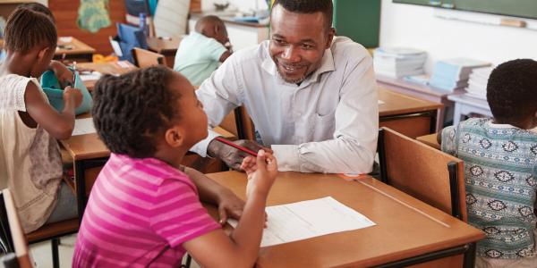 Male teacher helping student in classroom