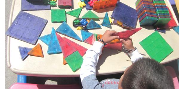 Child stacking brightly colored shapes