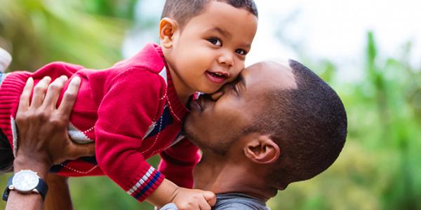 Father lifting his son into the air and kissing his cheek