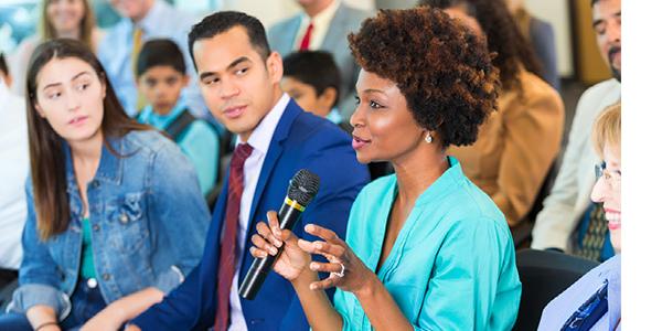 woman talking on a microphone while an audience listens attentively