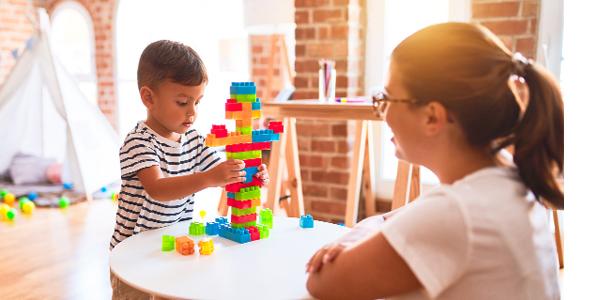 Teacher and preschooler building with colored blocks