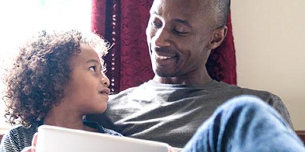 father and son with ipad smiling