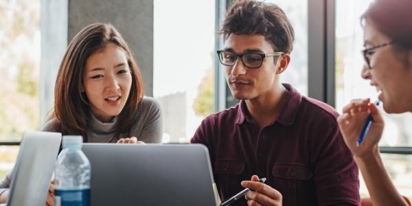 A group of diverse educators reviewing information on a laptop