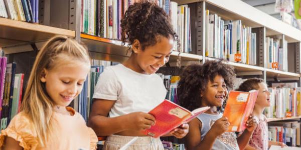 Three children reading books in a library
