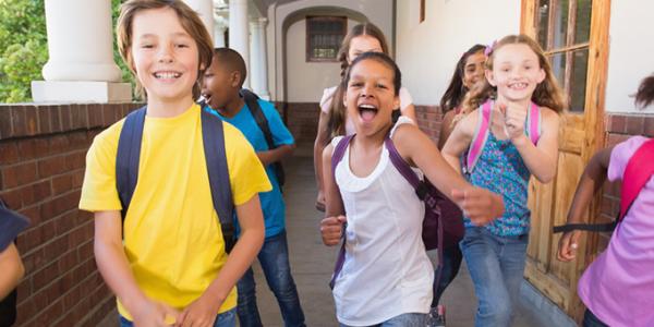 Children wearing backpacks in school hallway