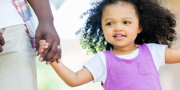 Girl holding hands with parents outside