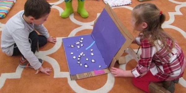 Two children creating a project with cardboard box