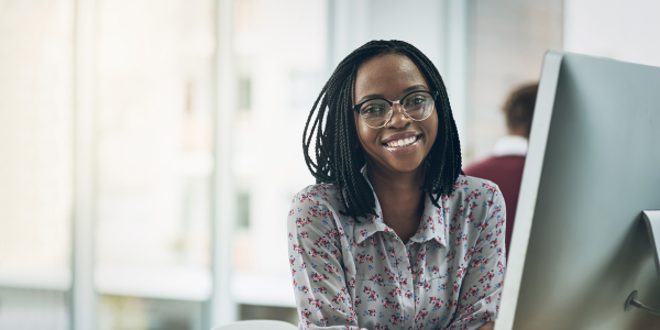 woman sitting at a computer screen smiling