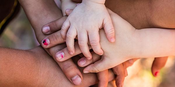 children and adult hands layered one on top of the other. 