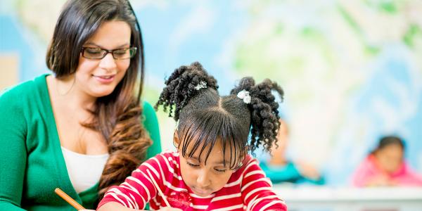 a teacher writing with a child at a table