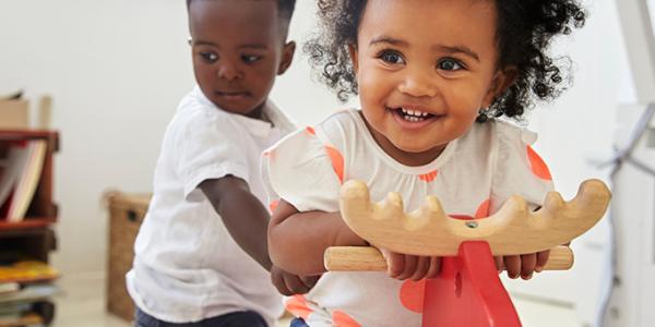 Two children playing on wooden horse