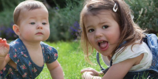 A baby and toddler playing outdoors