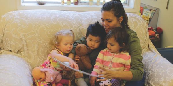Teacher reading a children's book to three toddlers