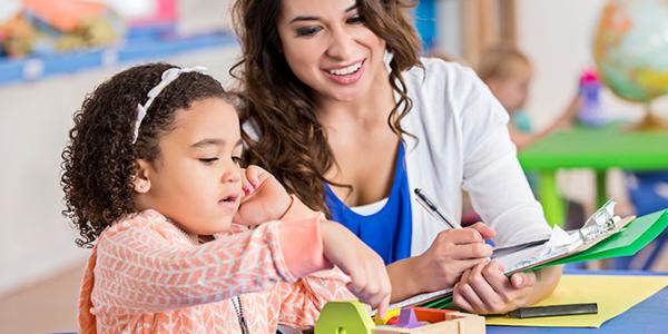 Teacher assessing preschool student play with toy