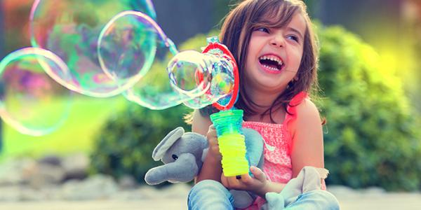 Child plays with bubbles outside