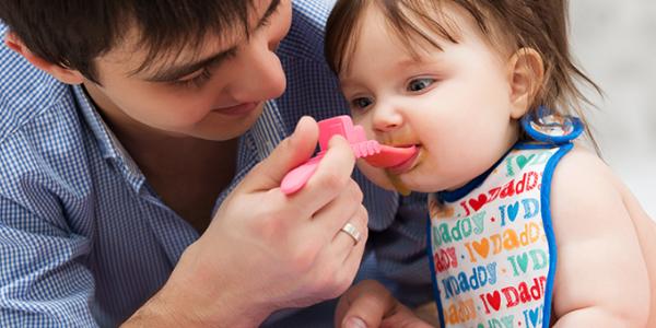 Male family child care provider feeding an infant