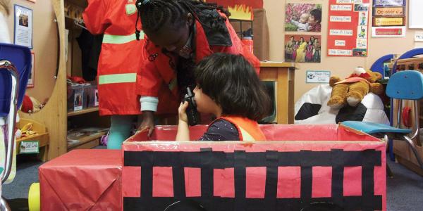 Child pretending to be a firefighter in a cardboard firetruck