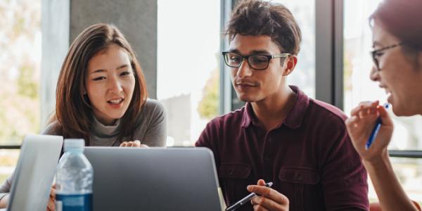 Four young professionals are looking at a computer screen.