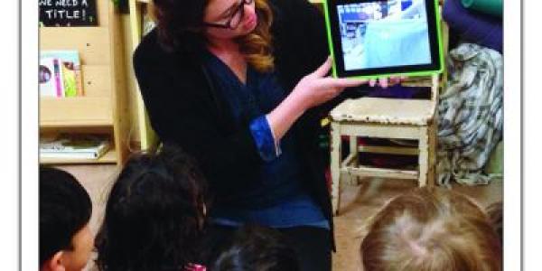 Teacher showing children a video of their previous day on a tablet.