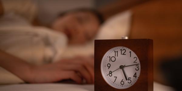 Image of a clock with a woman sleeping in the background