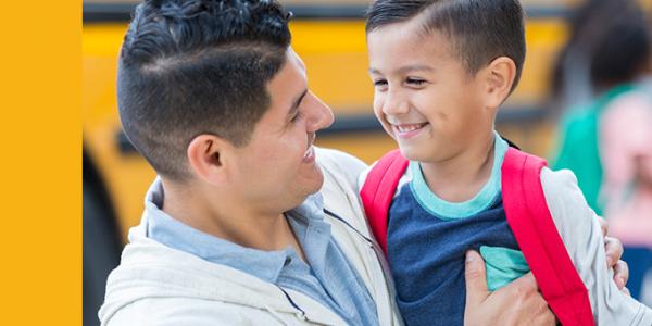 Father and son hugging by the school bus