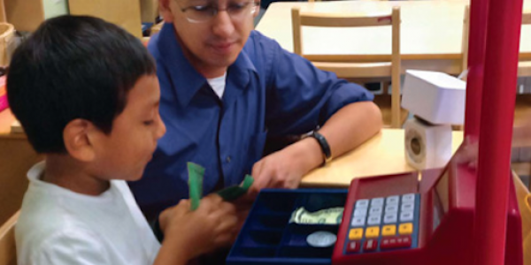 Teacher and student using a toy cash register