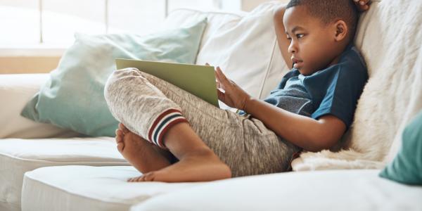 young preschool boy sitting on a couch reading
