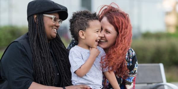 Two women interacting with a male toddler. 