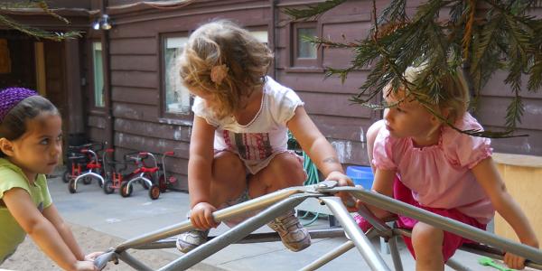 Three little girls playing together outside.