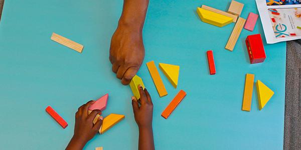 Teacher playing blocks with student.