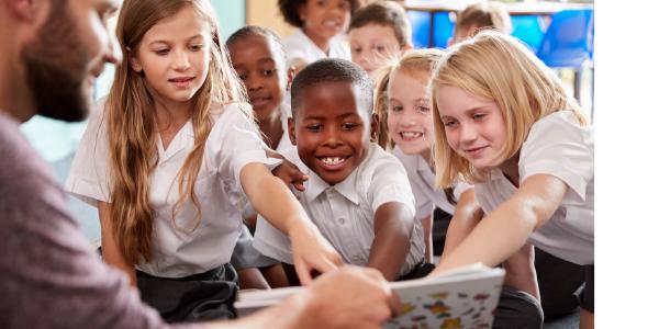 Teacher reading to the class while children point at the book