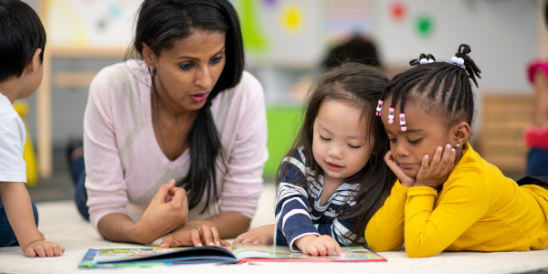 a teacher reading a picture book with children