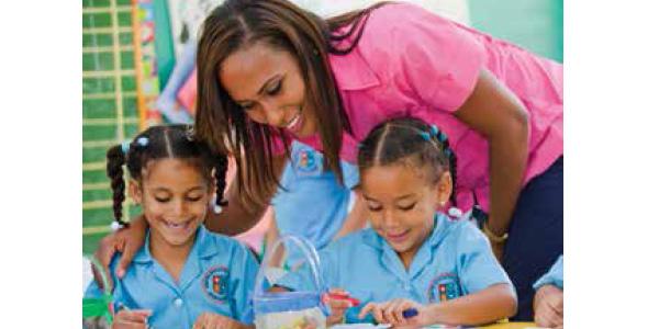 Teacher helping two students with writing 