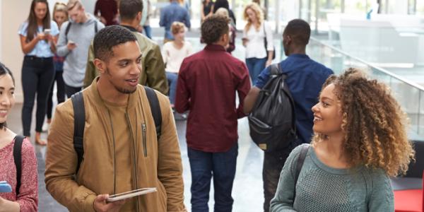 Three young adults walking and talking in a conference setting.