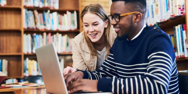 Two young professionals on a computer in the library