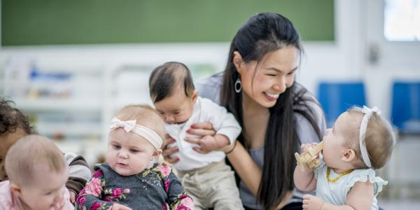 Teacher in a classroom with babies sitting on the floor with blocks