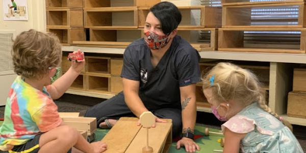 Teaching in a classroom with two children, playing with blocks.
