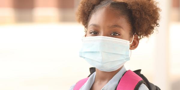 Young girl in a mask with a backpack on