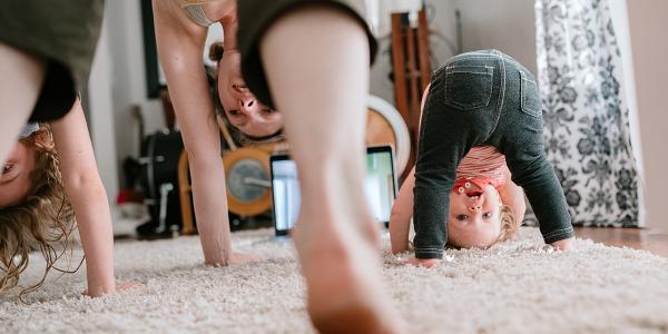 mother and two young girls doing yoga in the living room
