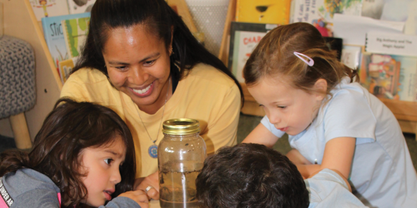 Feature Teacher Cecilia Fowler with students looking in a jar