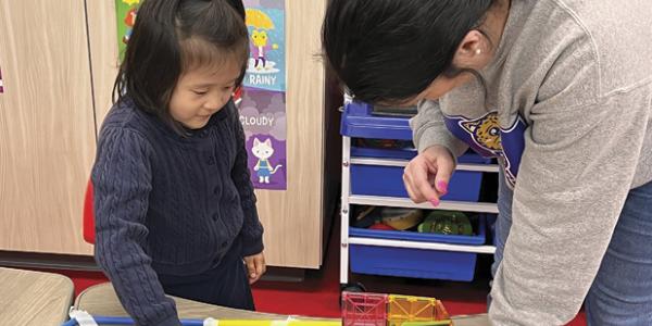 a young girl and a teacher playing with a craft