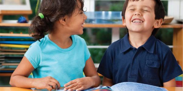 Two children enjoying reading a book.