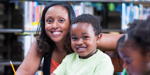 Woman and son sitting in the library smiling.
