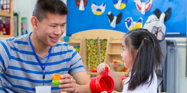 Teacher and young child playing at the water table in the classroom