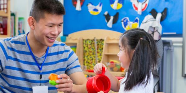 Teacher and young child playing at the water table in the classroom